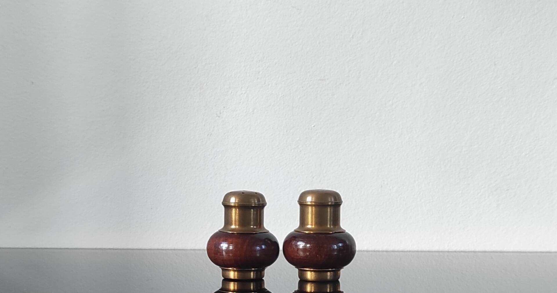 Vintage salt and pepper shaker duo in brass and turned wood.