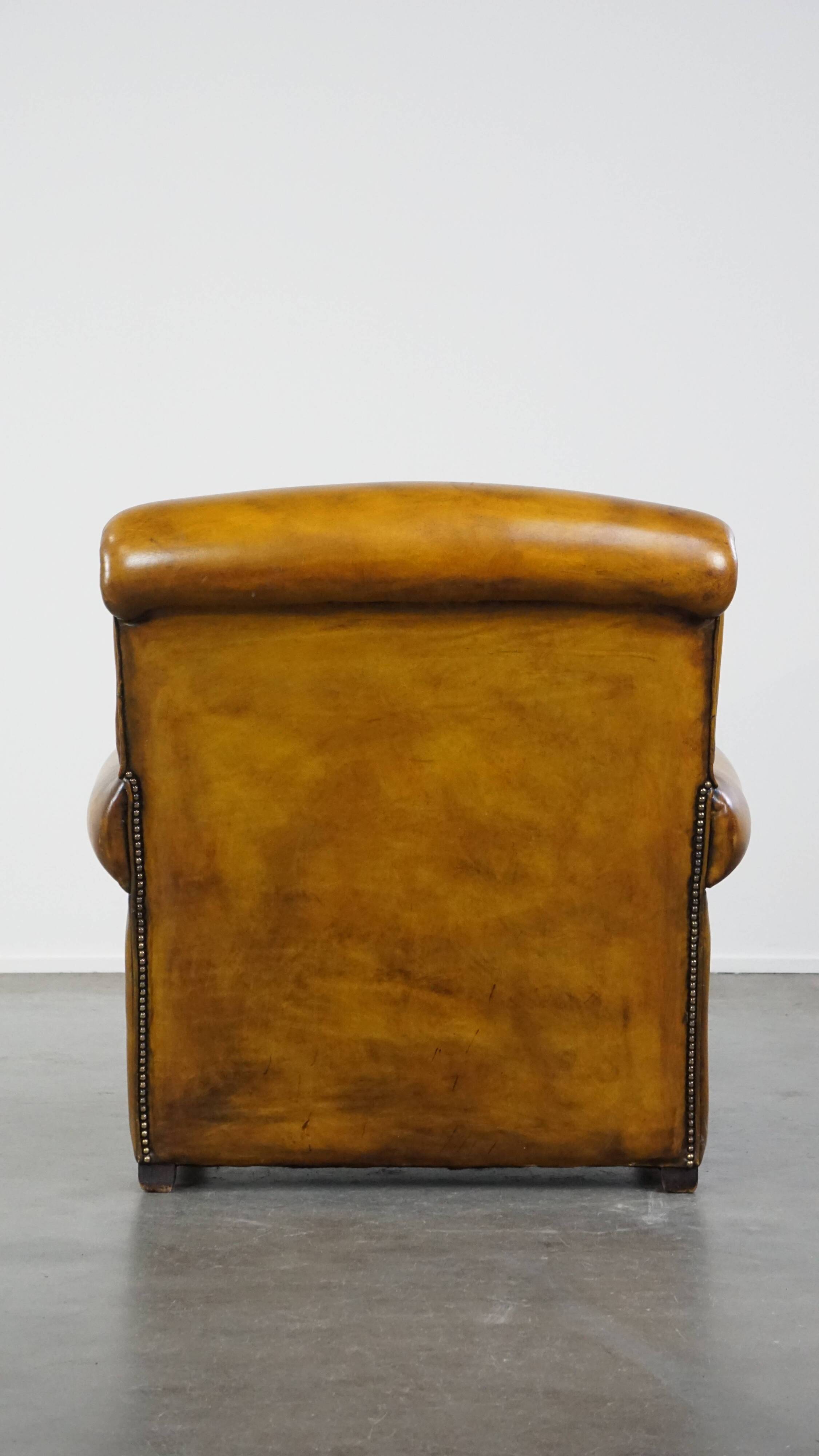 Comfortable large yellow English-style leather armchair with a fine finish and decorative nails