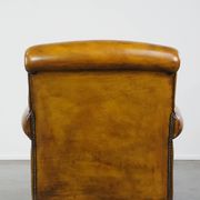 Comfortable large yellow English-style leather armchair with a fine finish and decorative nails