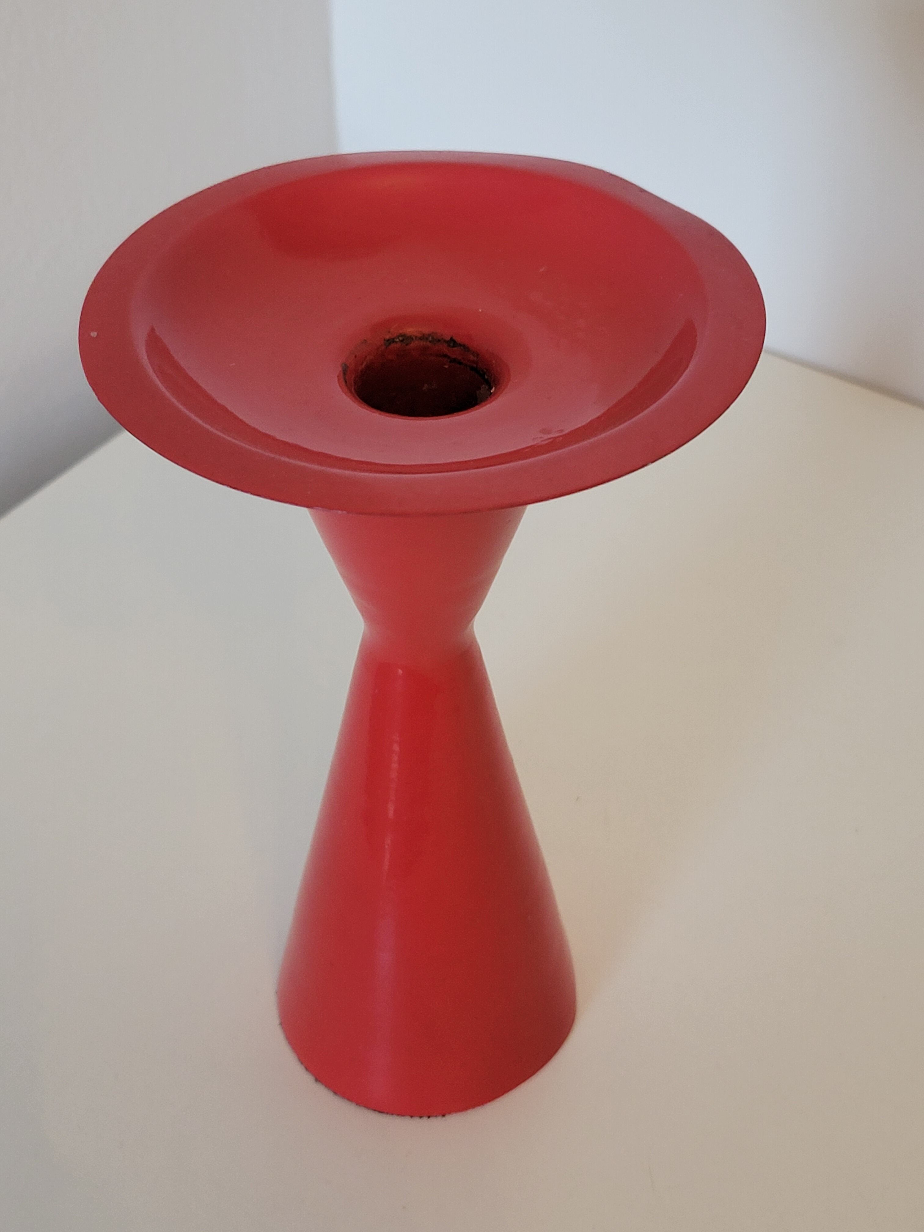 Vintage design candlestick in red metal in the shape of an hourglass