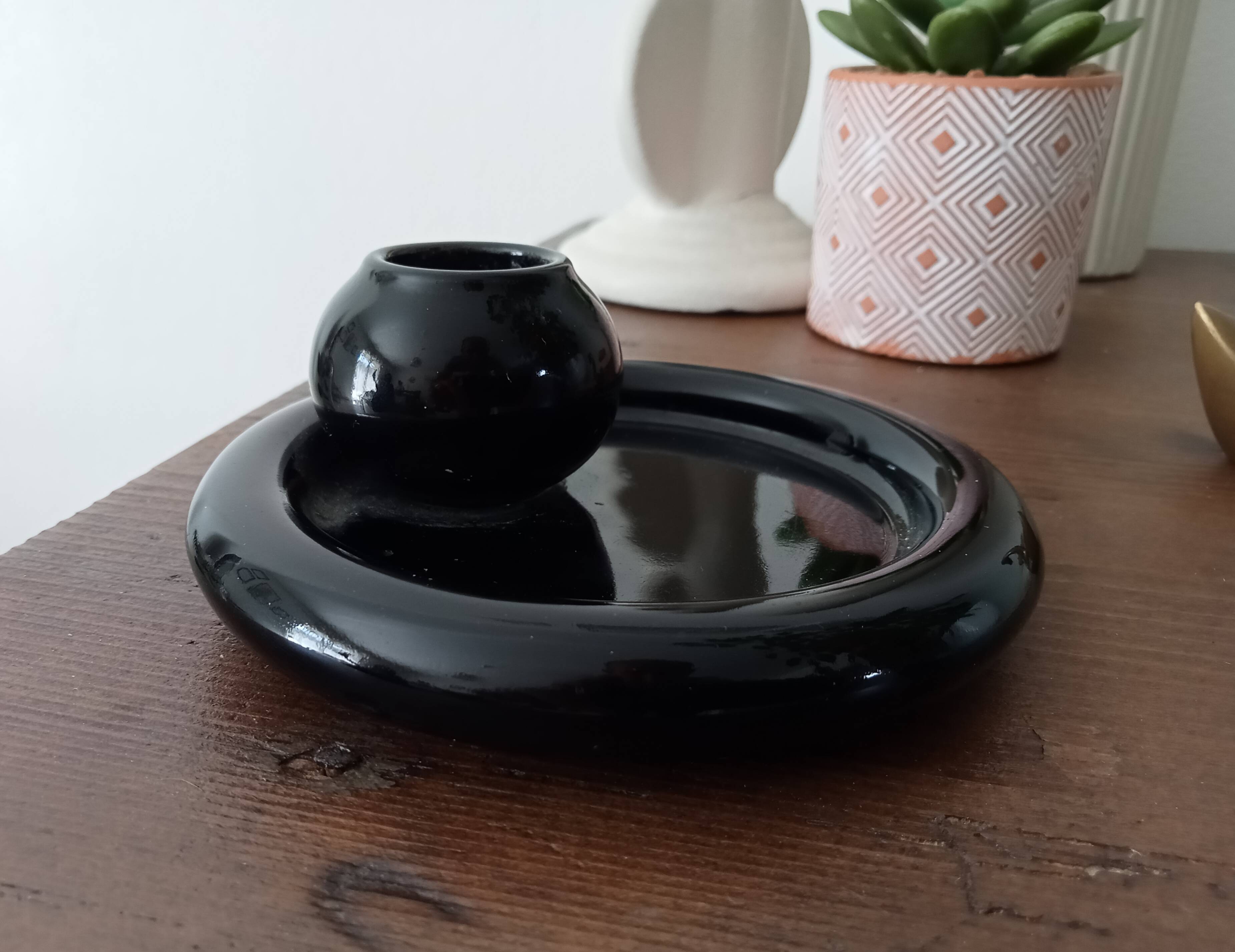 Vintage black ceramic candle holder on a bowl