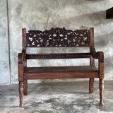 Small antique Indonesian bench in carved teak with plant and floral motifs.