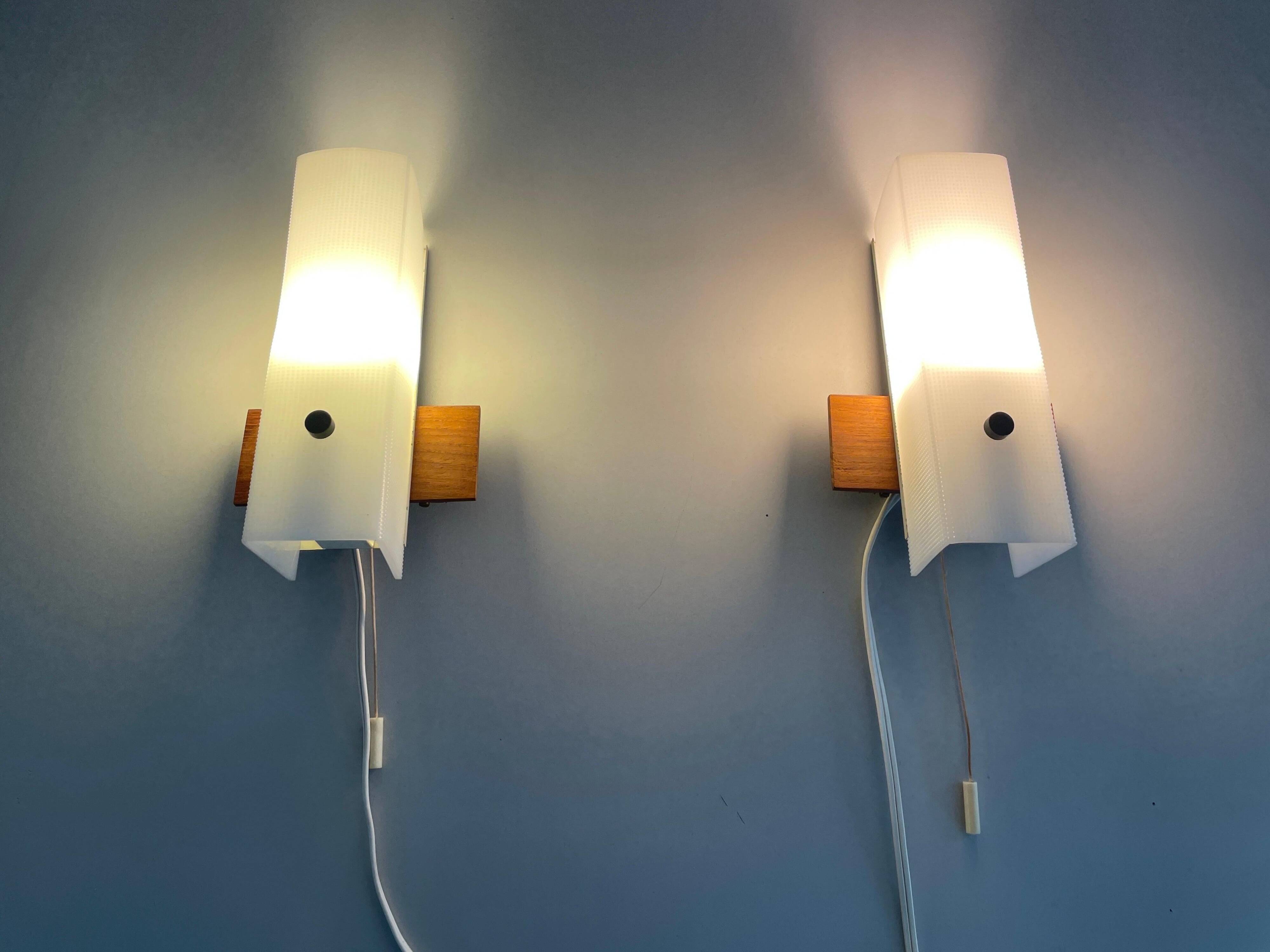 Mid-century wall lights in white plexiglass with a wooden base, 1960s, Germany.