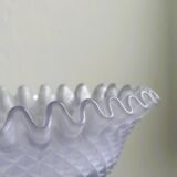 Purple glass pedestal bowl with wavy border and relief pattern.