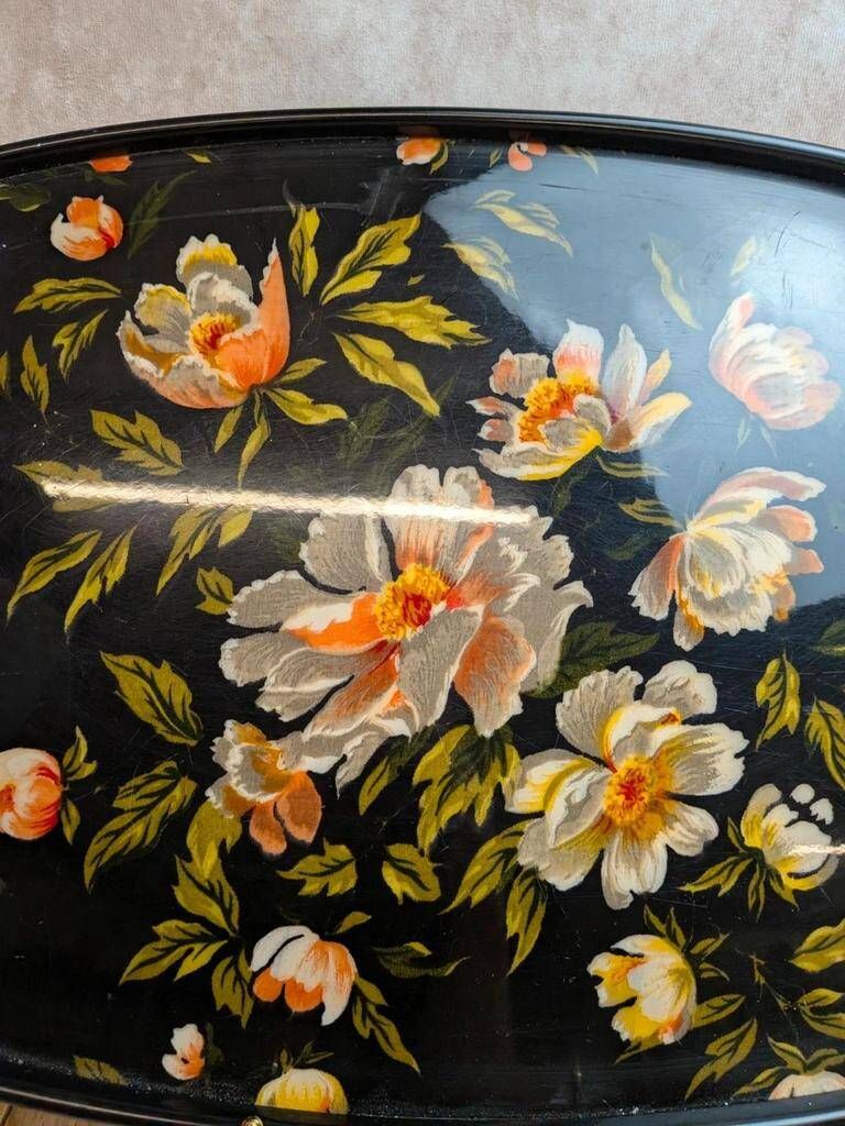 Large vintage 1960s platter with floral decoration on a black background and golden handles.