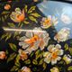 Large vintage 1960s platter with floral decoration on a black background and golden handles.