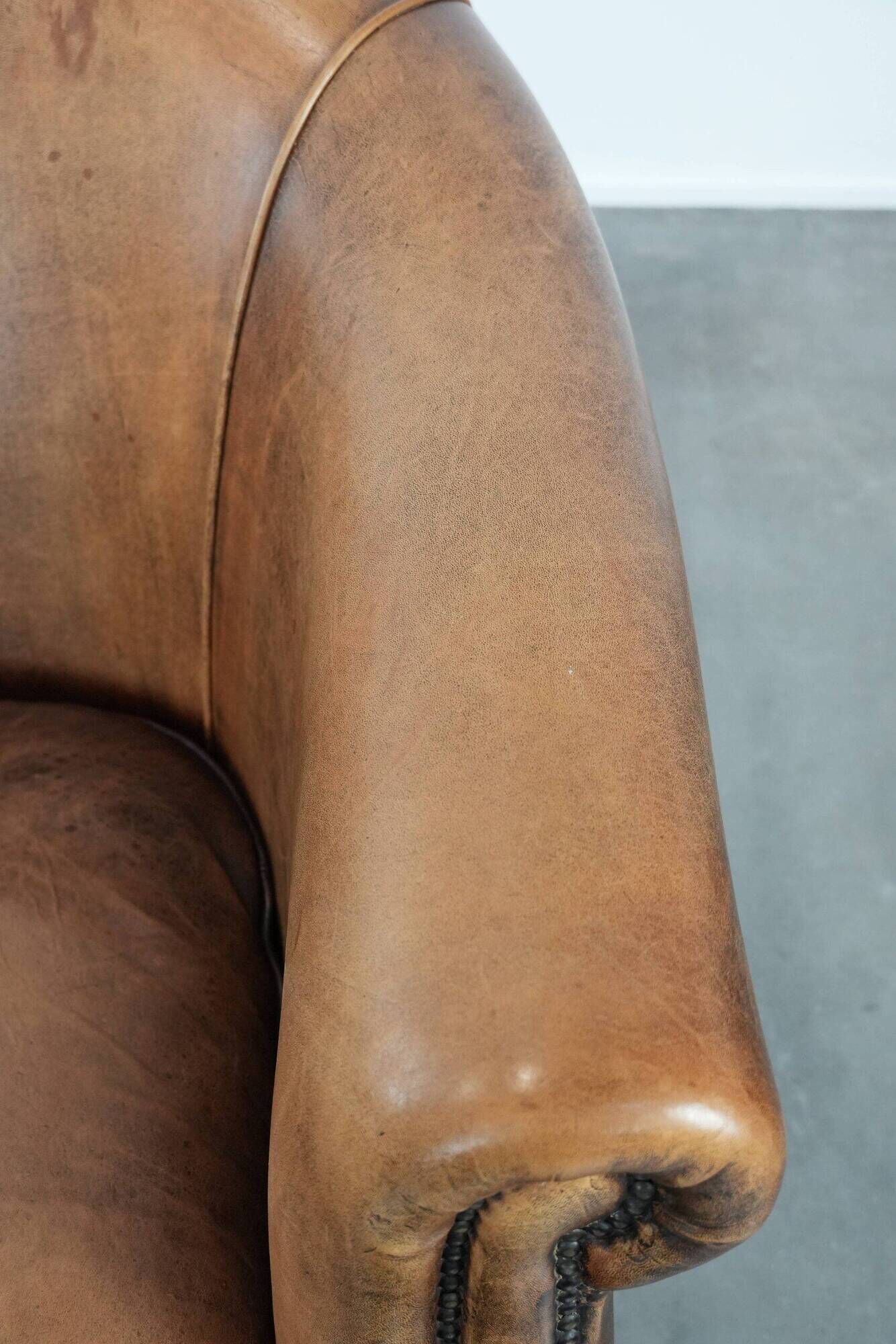 Club chair made of sheepskin leather finished with decorative nails