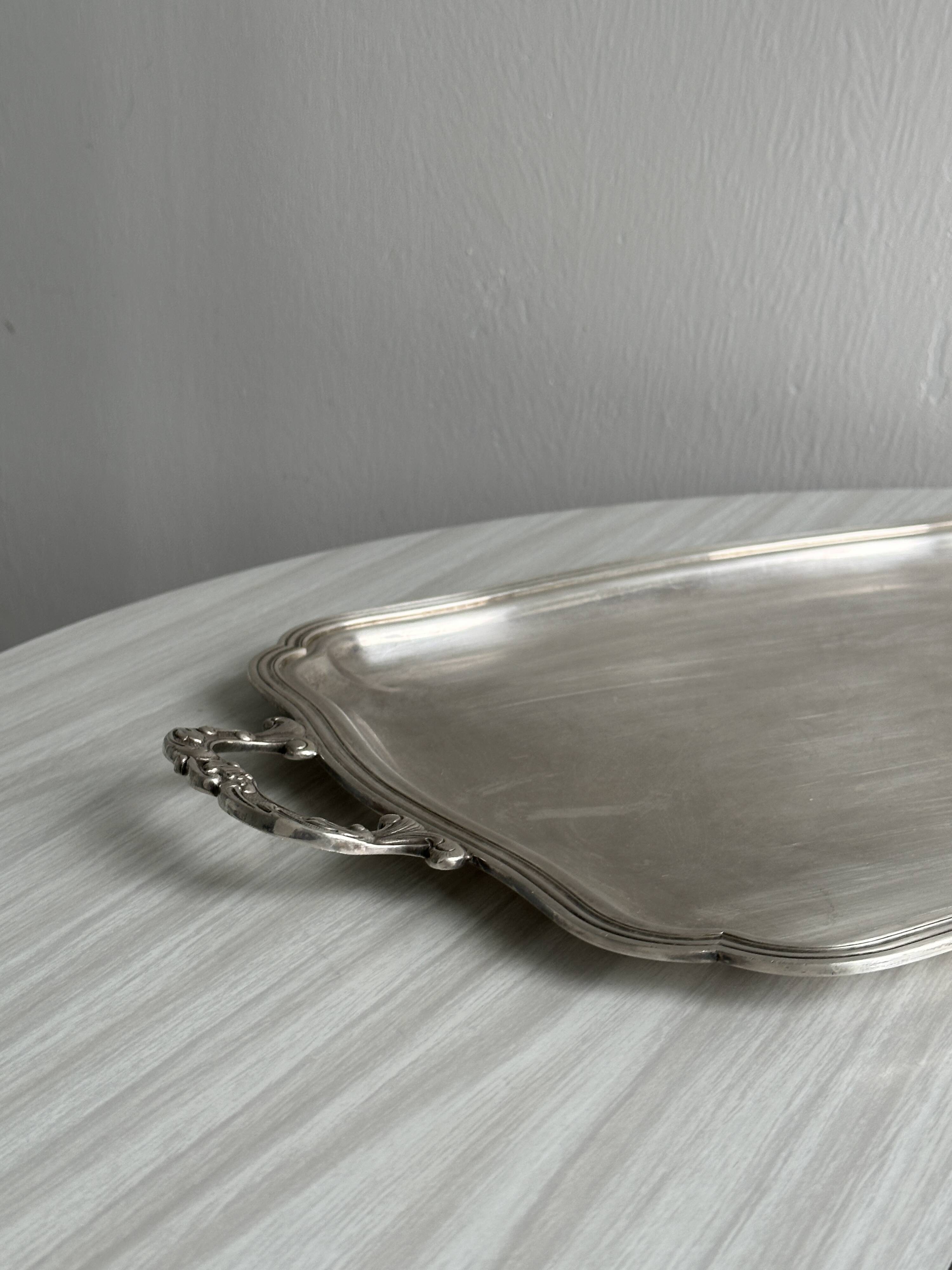 Silver metal serving tray with sculpted handles