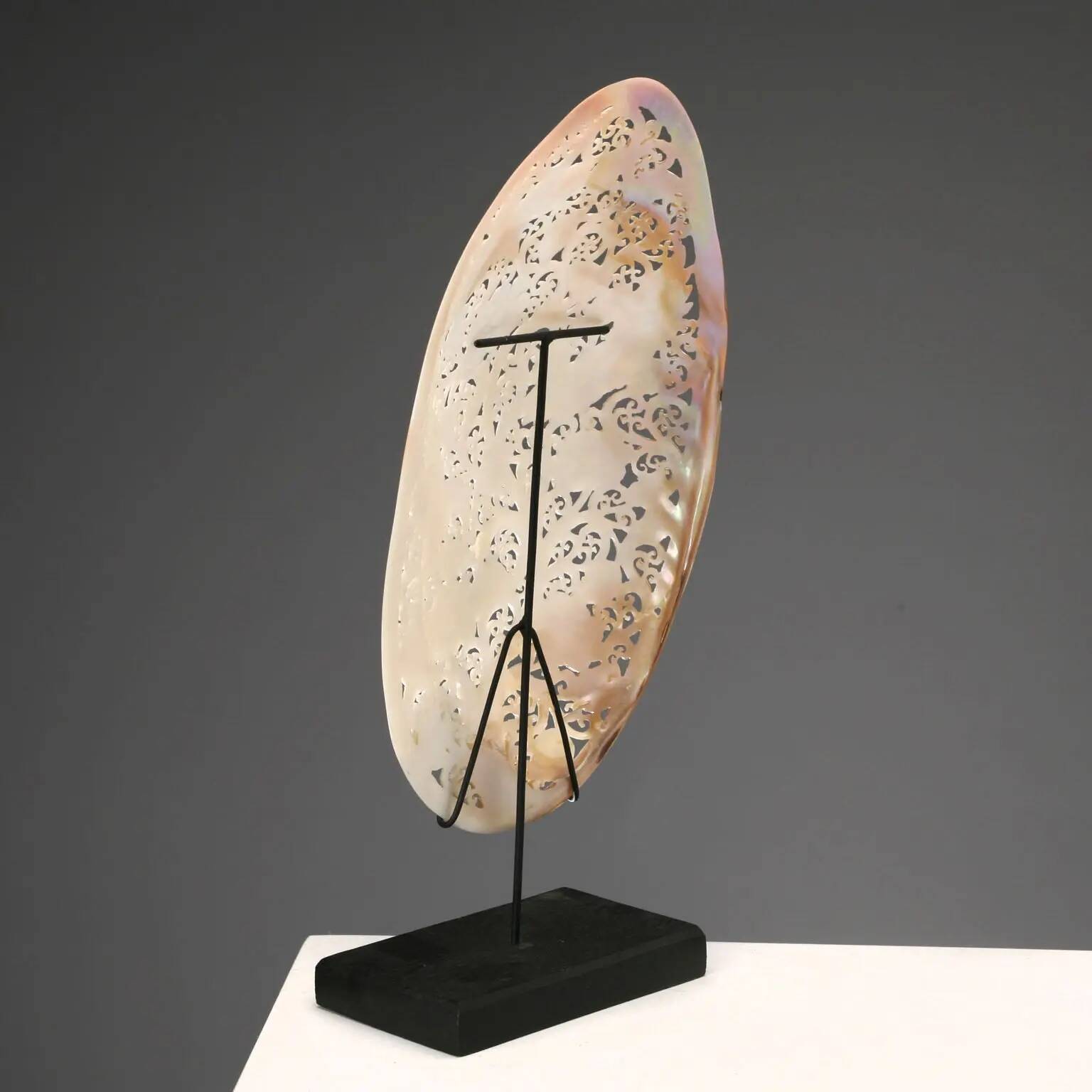 Perforated shell hand-decorated on a wooden base
