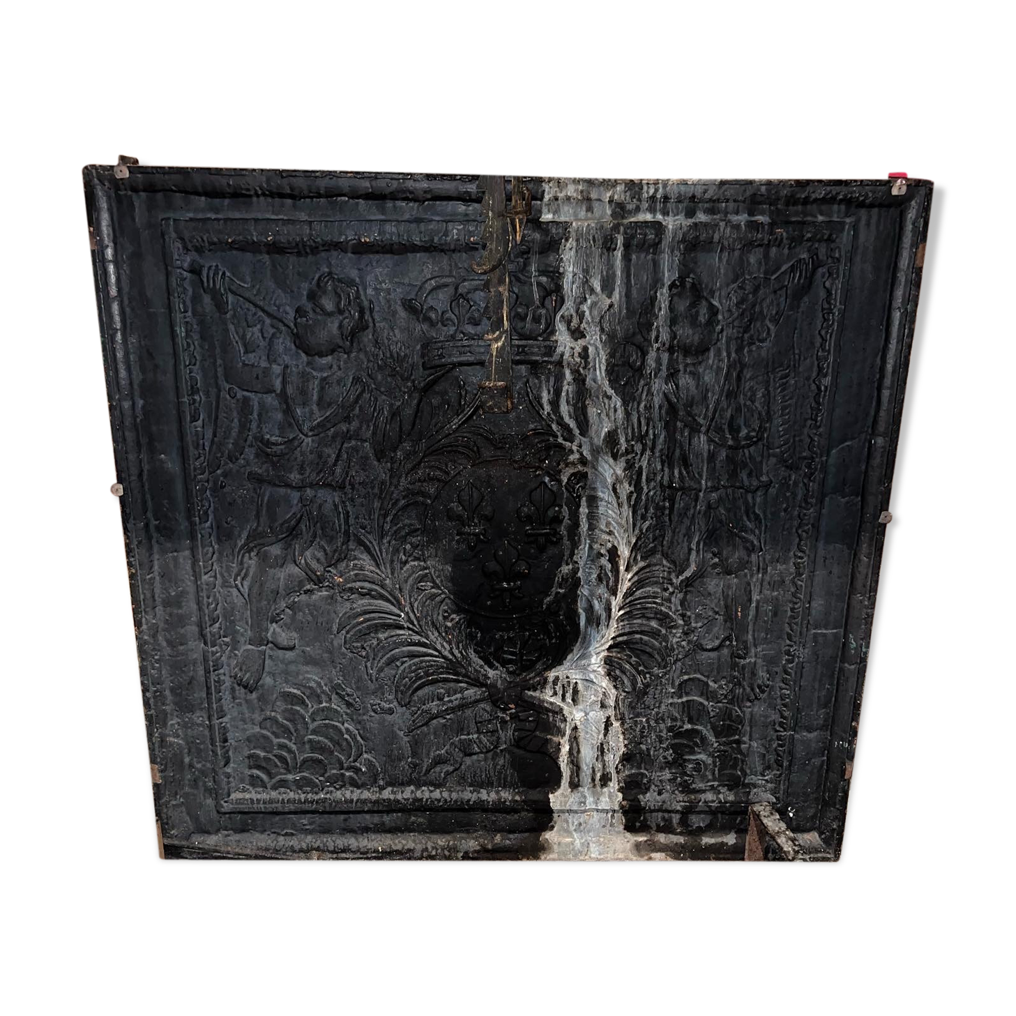 huge old fireplace plate has decoration of angels, crown and fleurs-de-lis