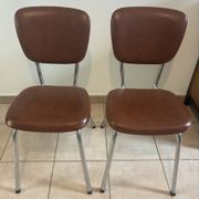 Two brown faux leather chairs.