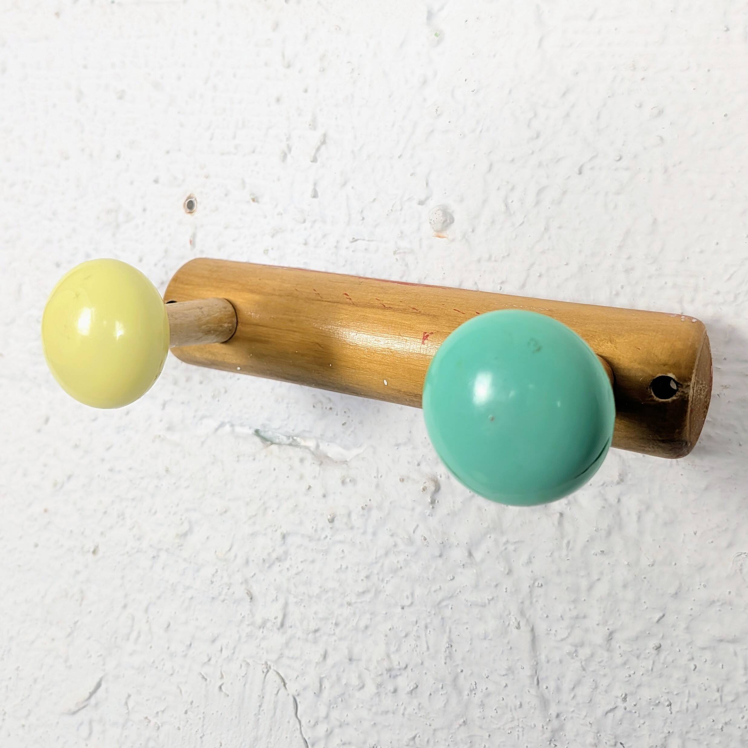 Vintage wall coat rack with 2 yellow and green balls.