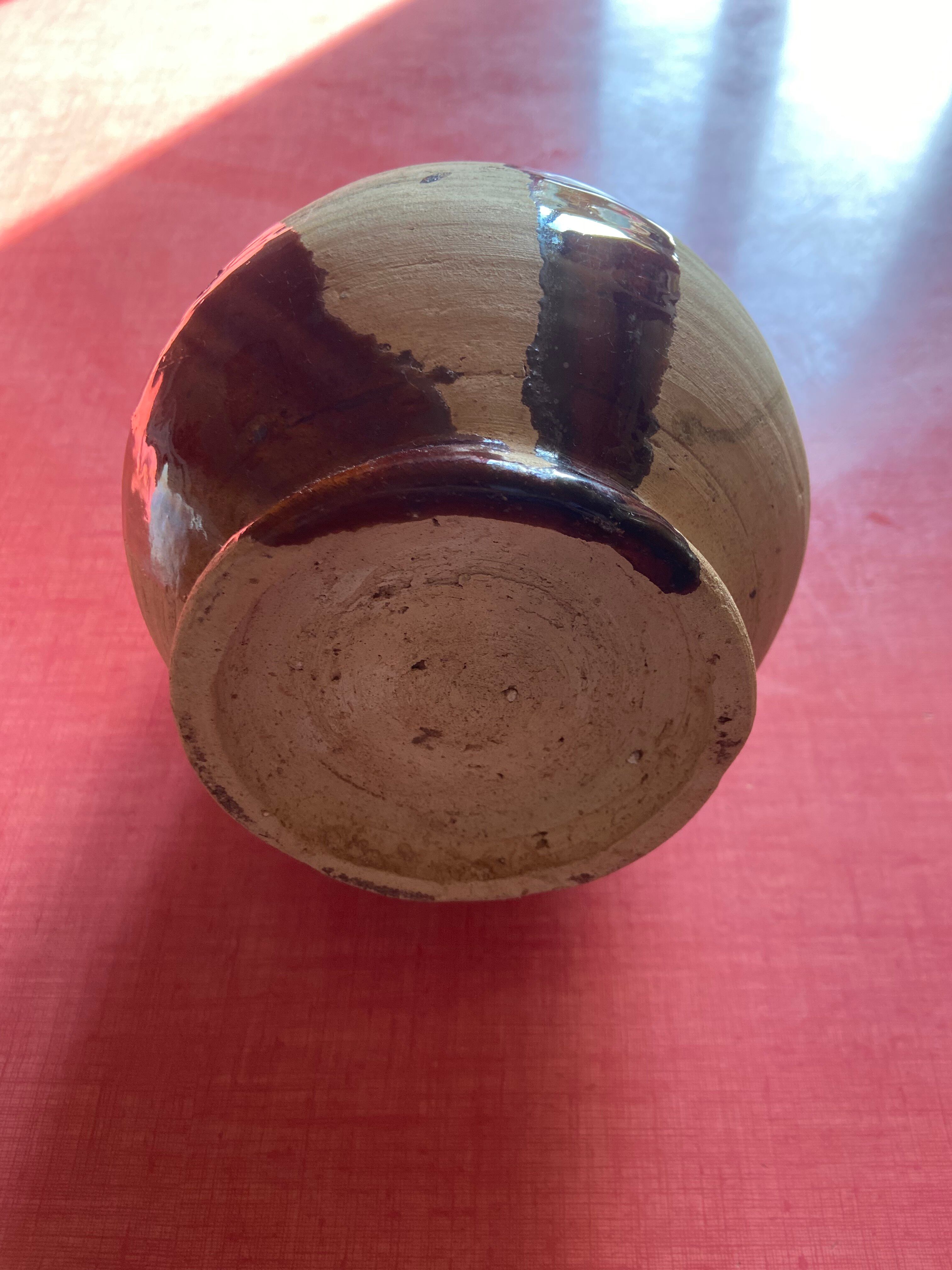 Large antique pottery bottle in glazed terracotta with drips.