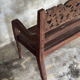 Small antique Indonesian bench in carved teak with plant and floral motifs.