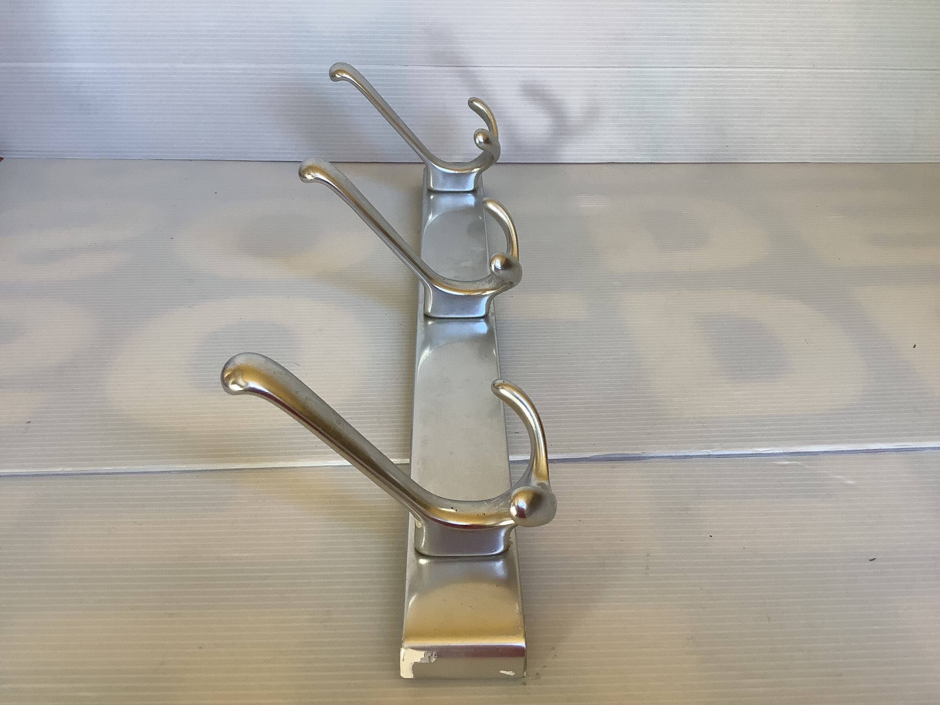 Stainless steel coat rack with three double hooks.
