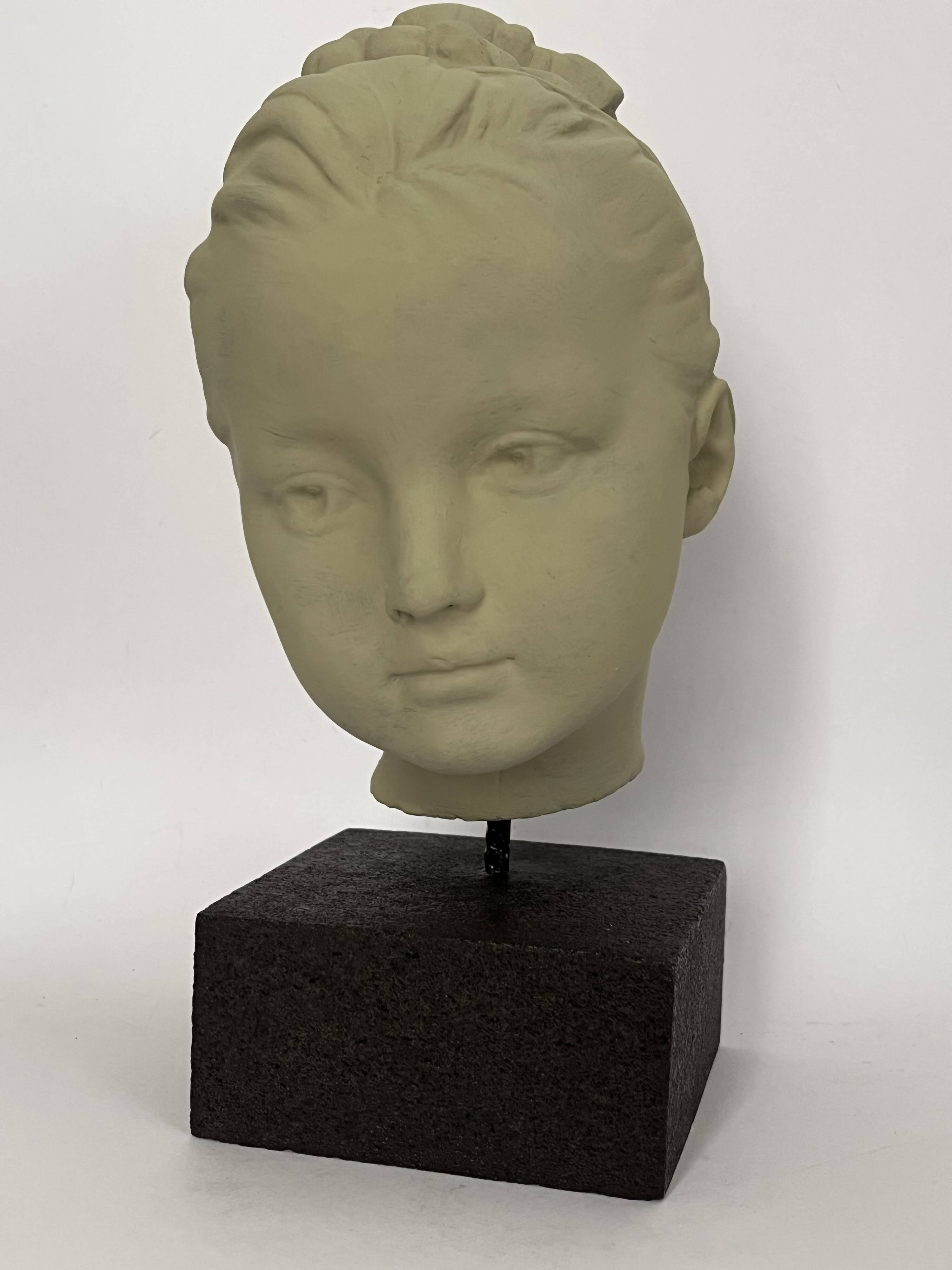 Plaster head of a young girl on a pedestal.