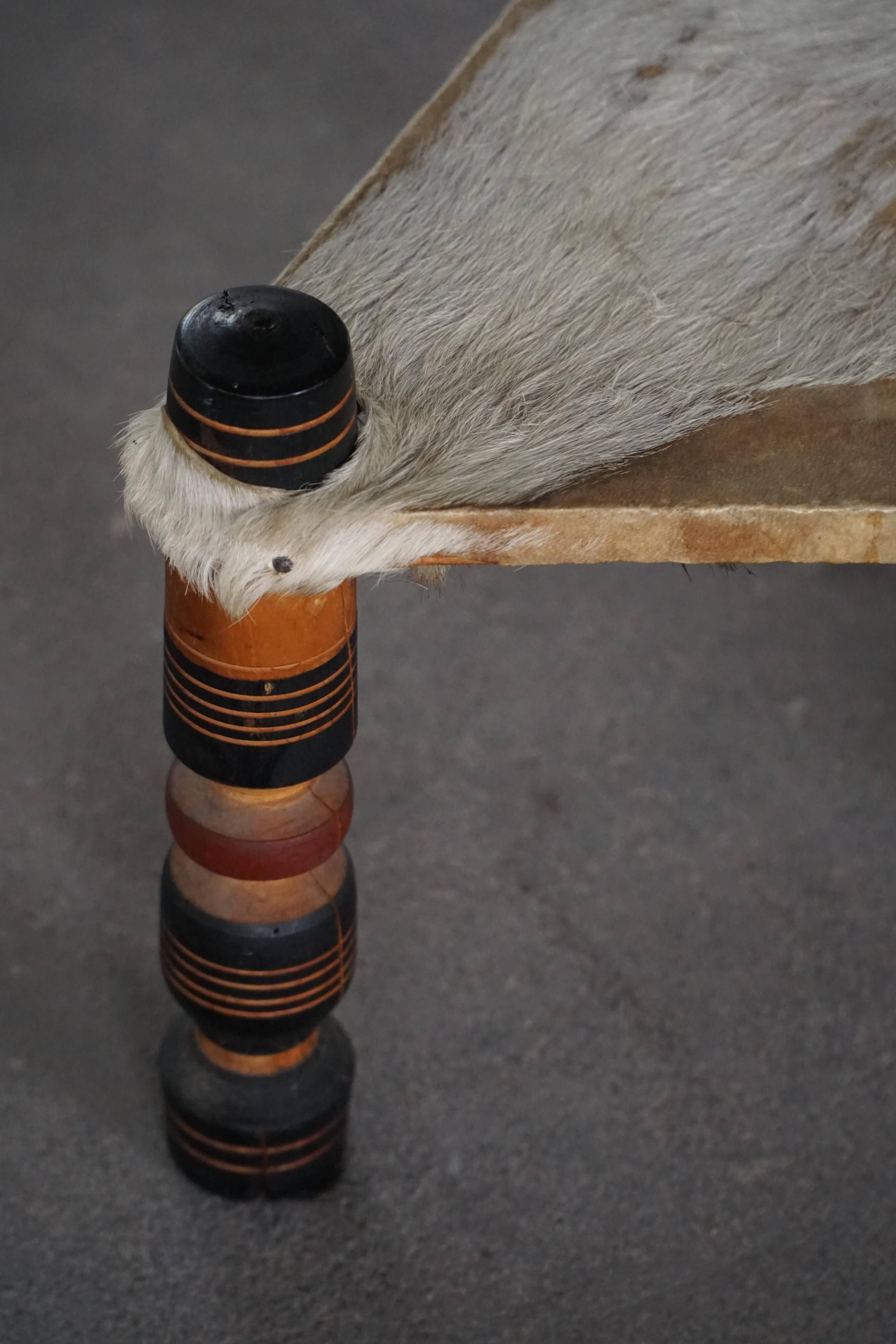 Vintage African artisanal stool, triangular shape with 3 legs, cowhide, 20th century.