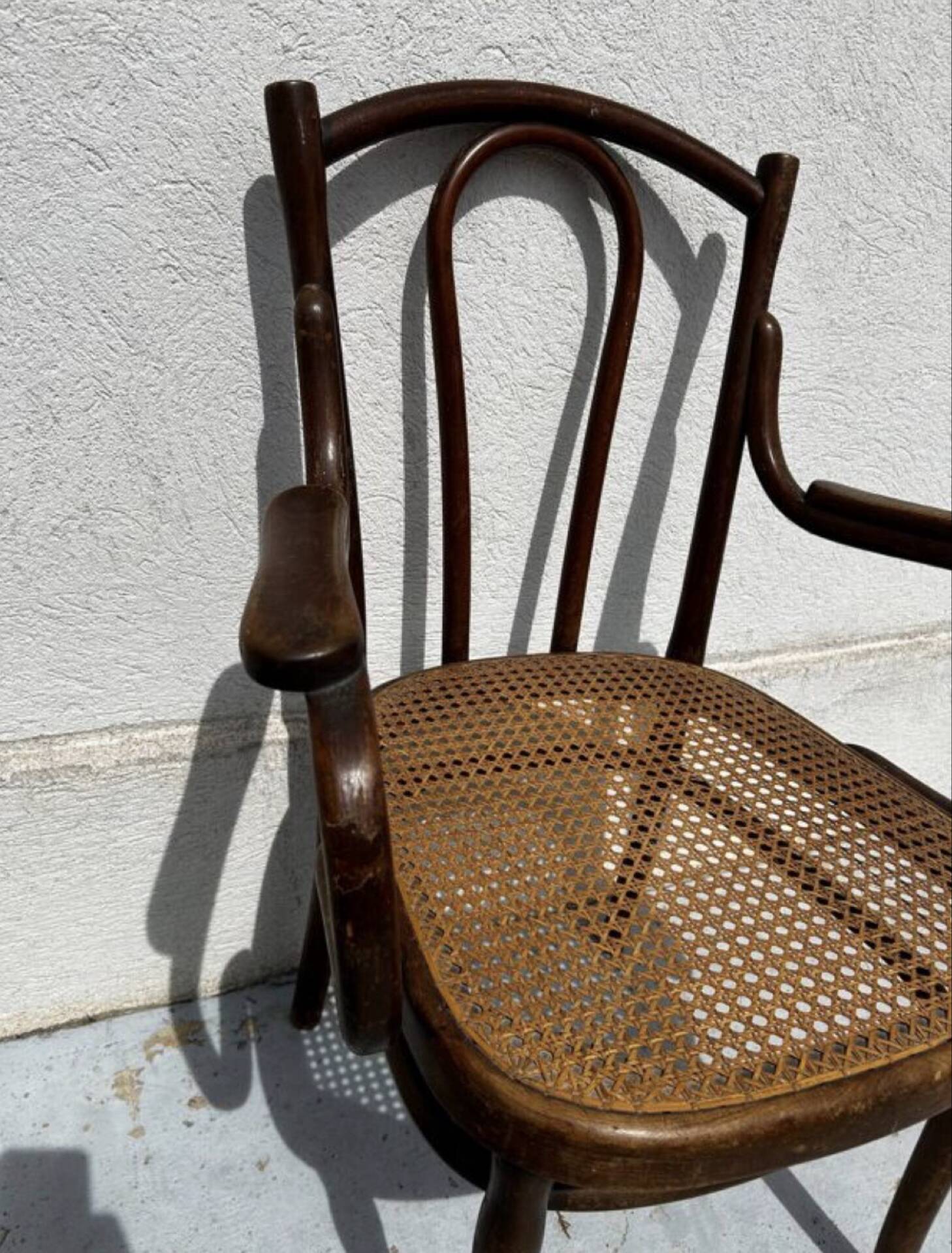 Thonet armchair stamped with curved wooden armrests and caning from the 19th century.