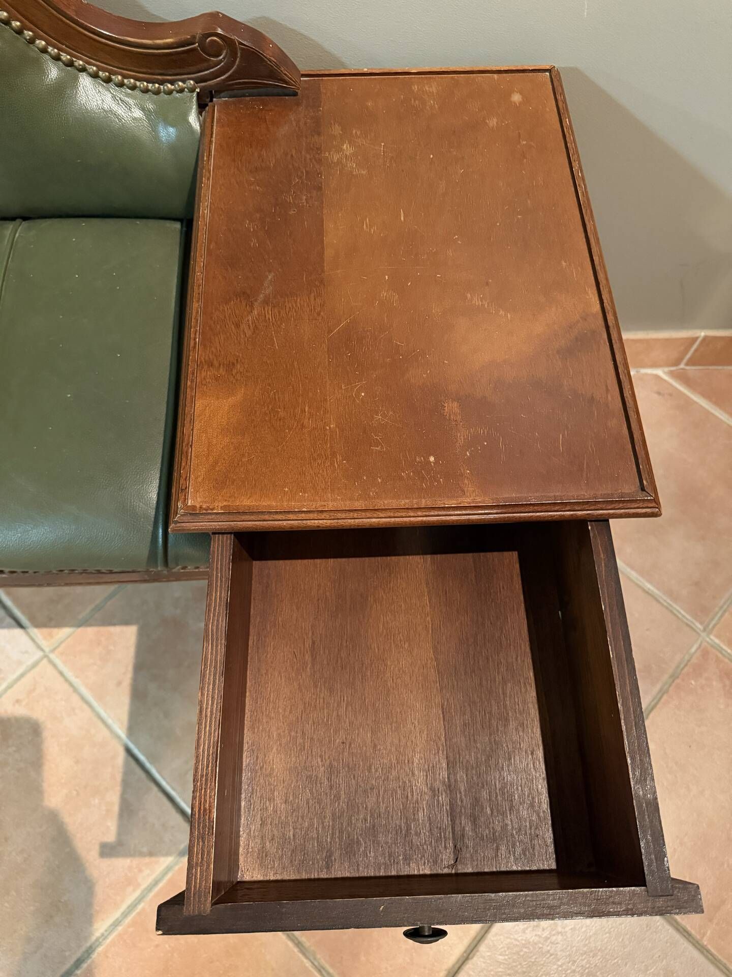 Antique carved wooden bench with green upholstered seat and backrest.