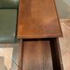 Antique carved wooden bench with green upholstered seat and backrest.