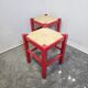 Tabouret en bois rouge avec assise en paille tressée.