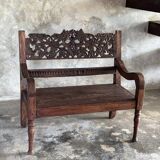 Small antique Indonesian bench in carved teak with plant and floral motifs.