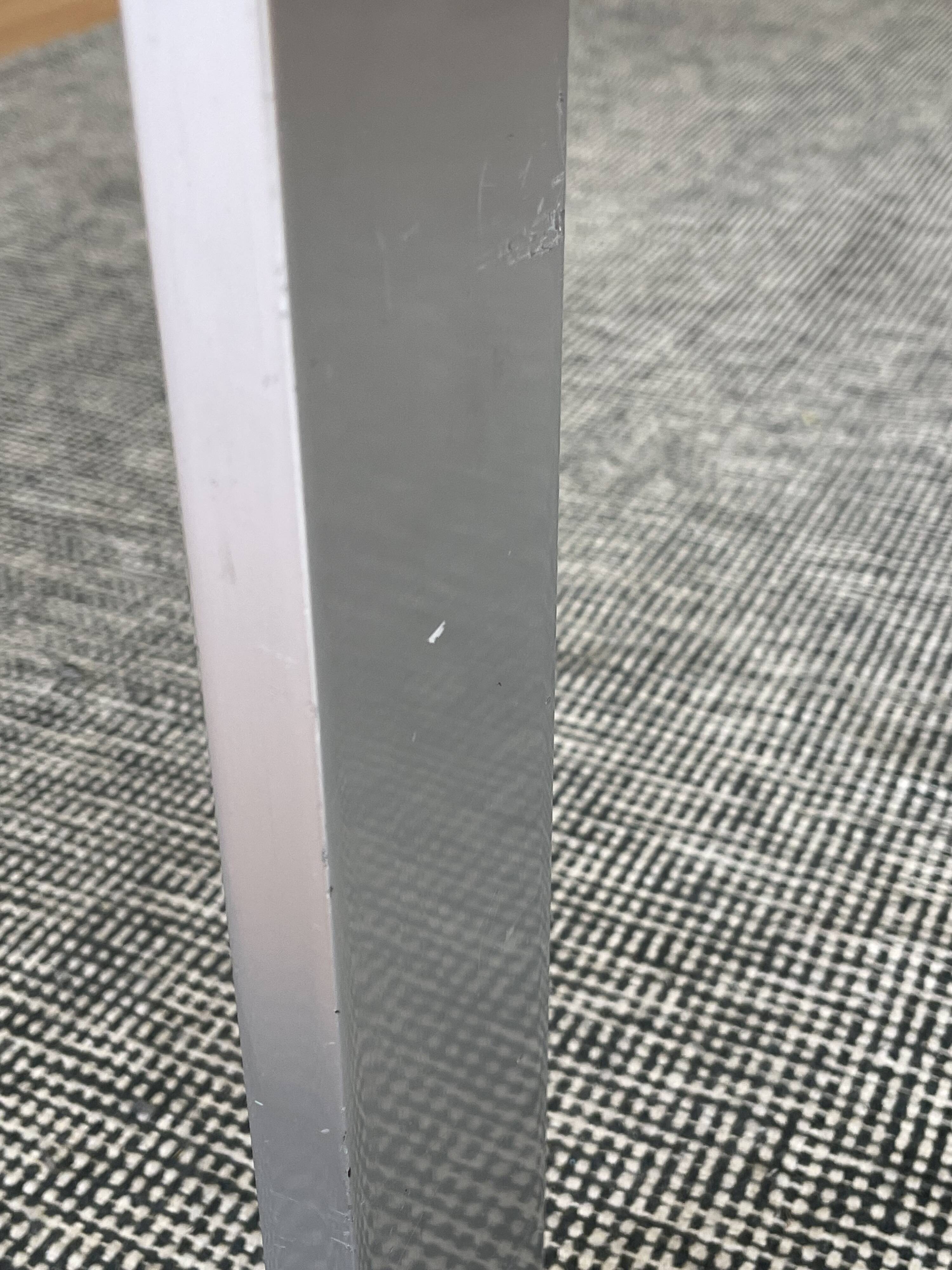 Round dining table with a glass top and brushed metal triangular frame.