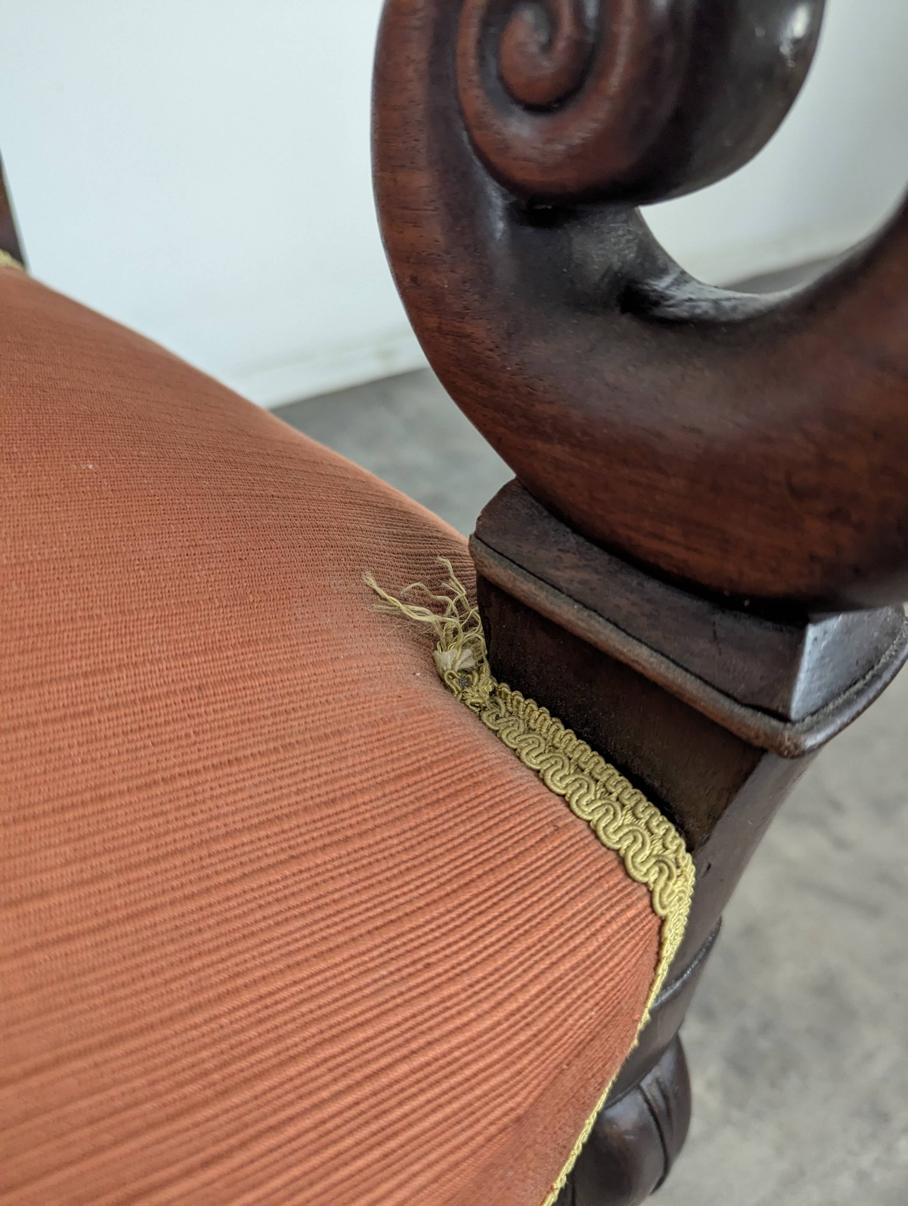 Restoration armchair in mahogany with cross arms and orange fabric.