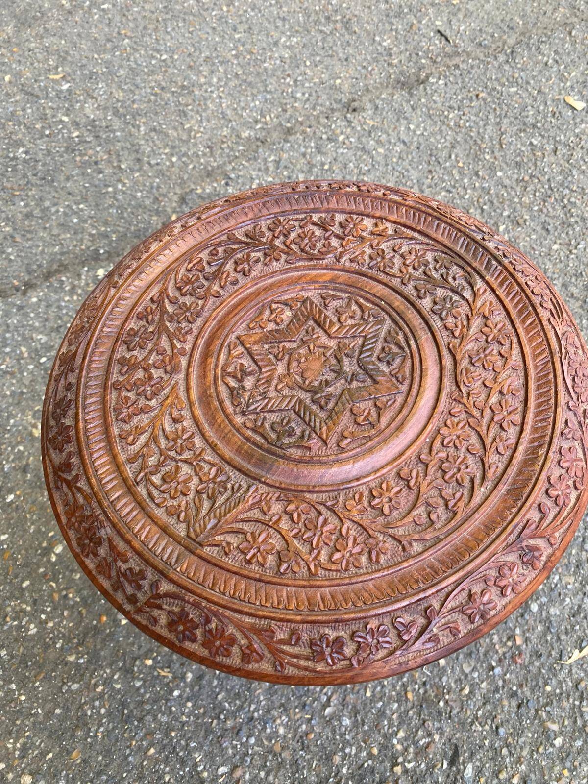 Round folding side table made of carved solid wood.