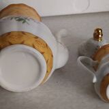 Golden porcelain teapot and coffee pot set with floral design and matching milk jug.