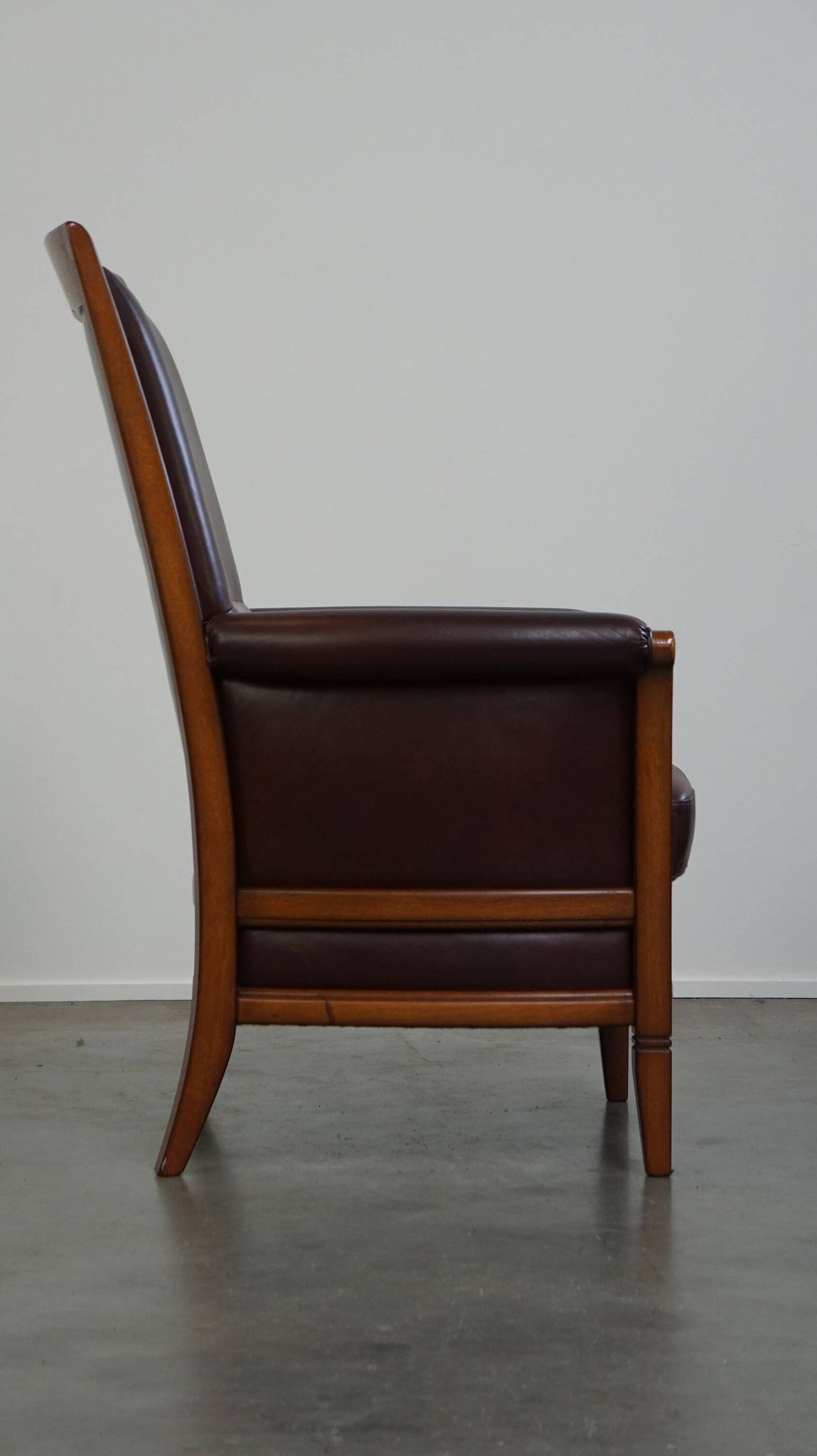 Very comfortable classic cowhide armchair with a high back in a mild Art Deco style