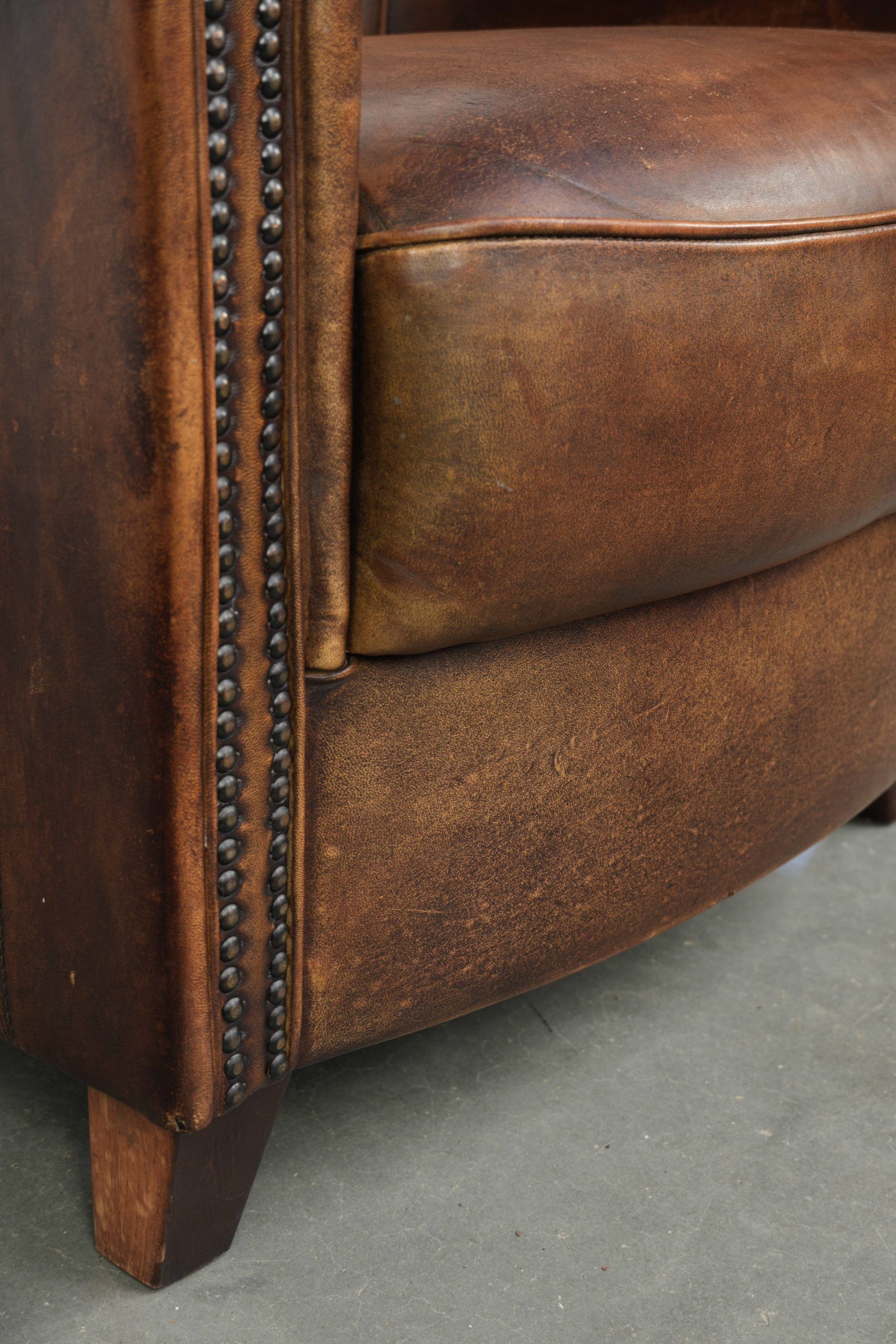 Sheepskin clubarmchair with beautiful patina finished with decorative nails