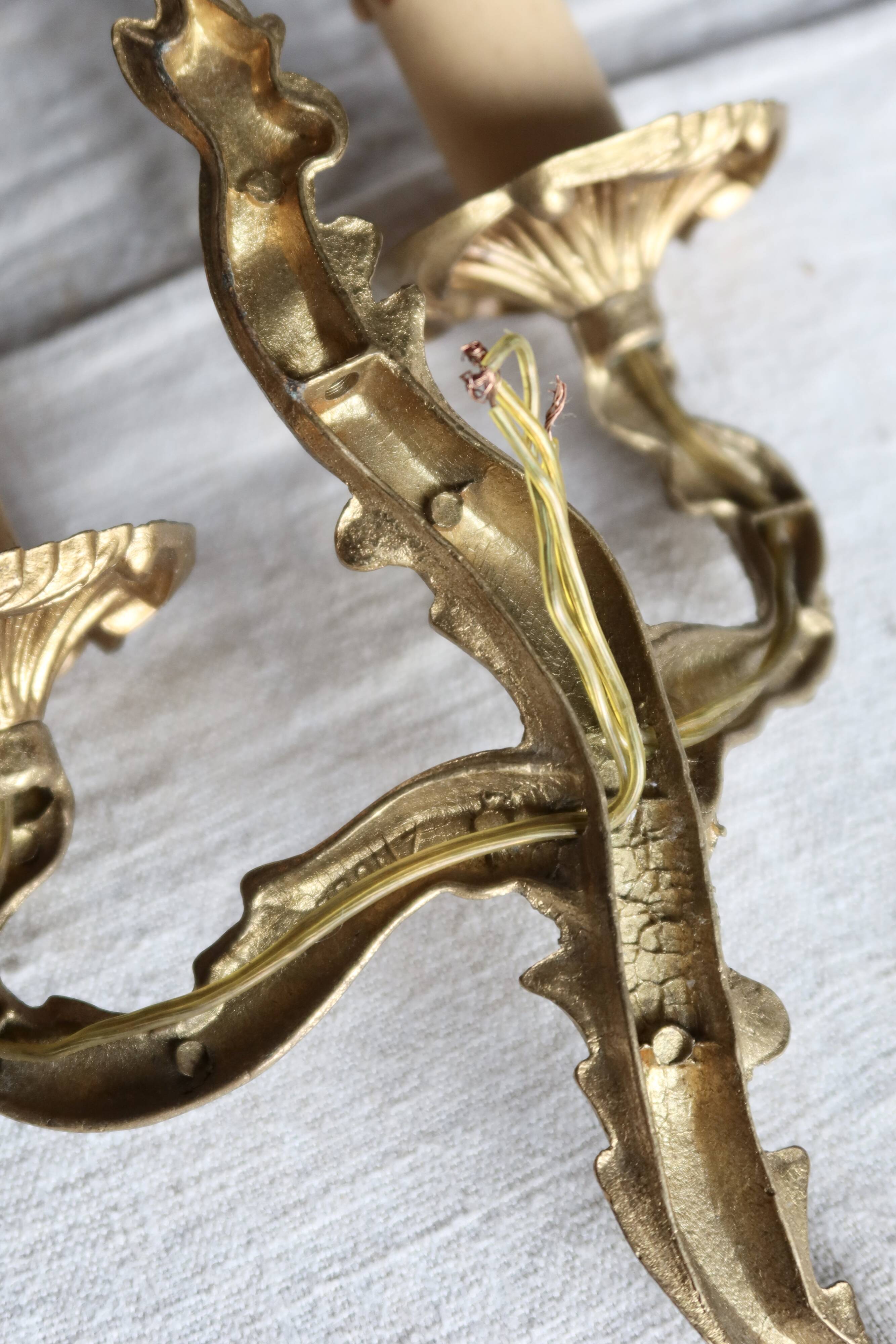Vintage wall sconce in gold metal with two arms in classic style.