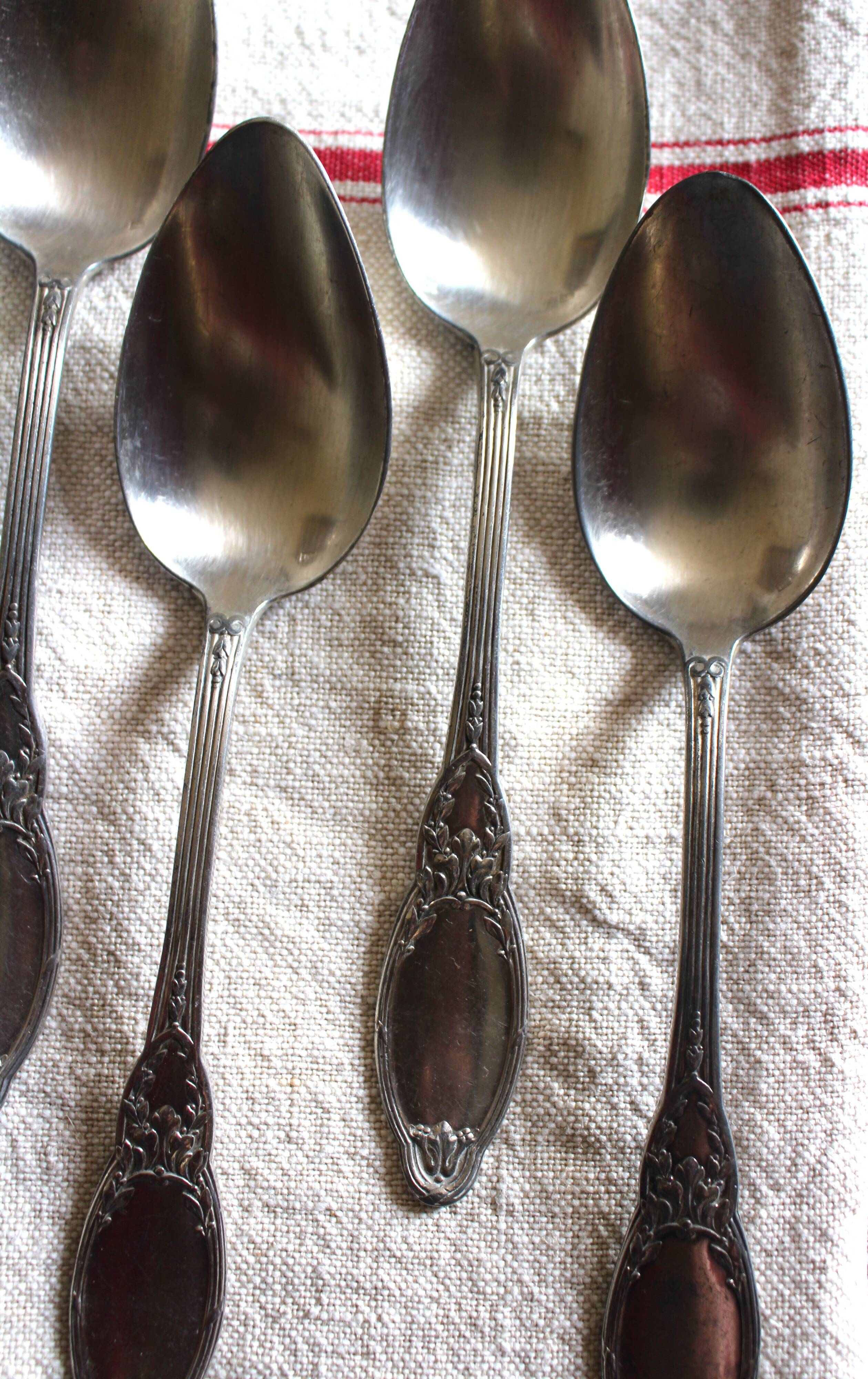 A set of 6 silver-plated metal soup spoons with foliage design.