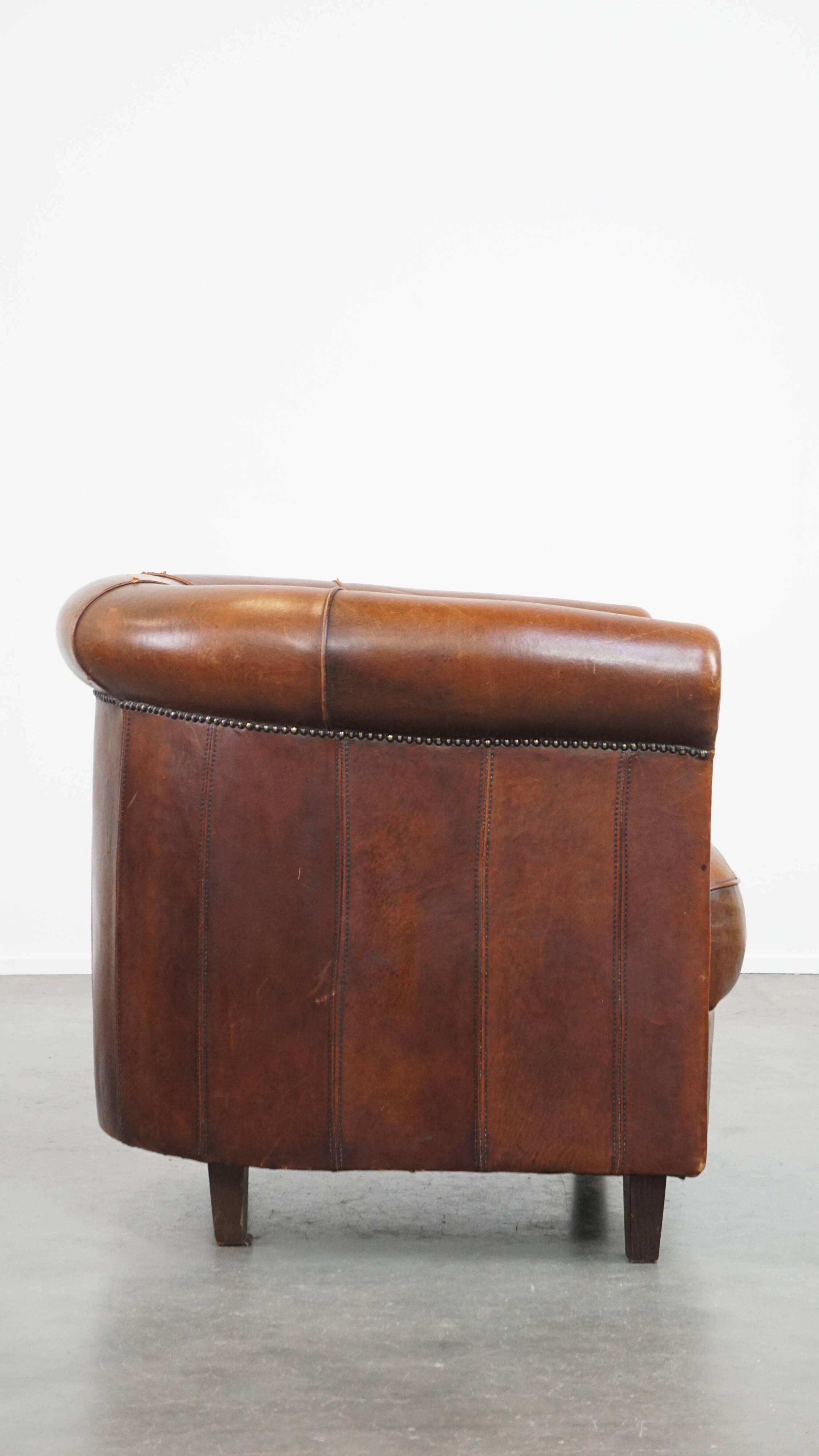 Sheep leather club chair in a cognac color and finished with piping