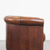 Sheep leather club chair in a cognac color and finished with piping