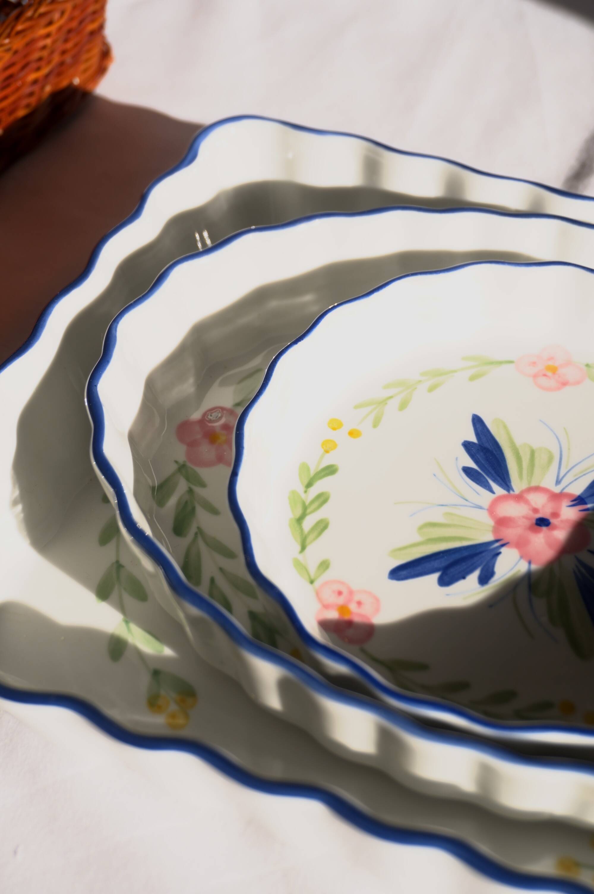 Set of 3 porcelain dishes with floral decorations, with wicker supports.