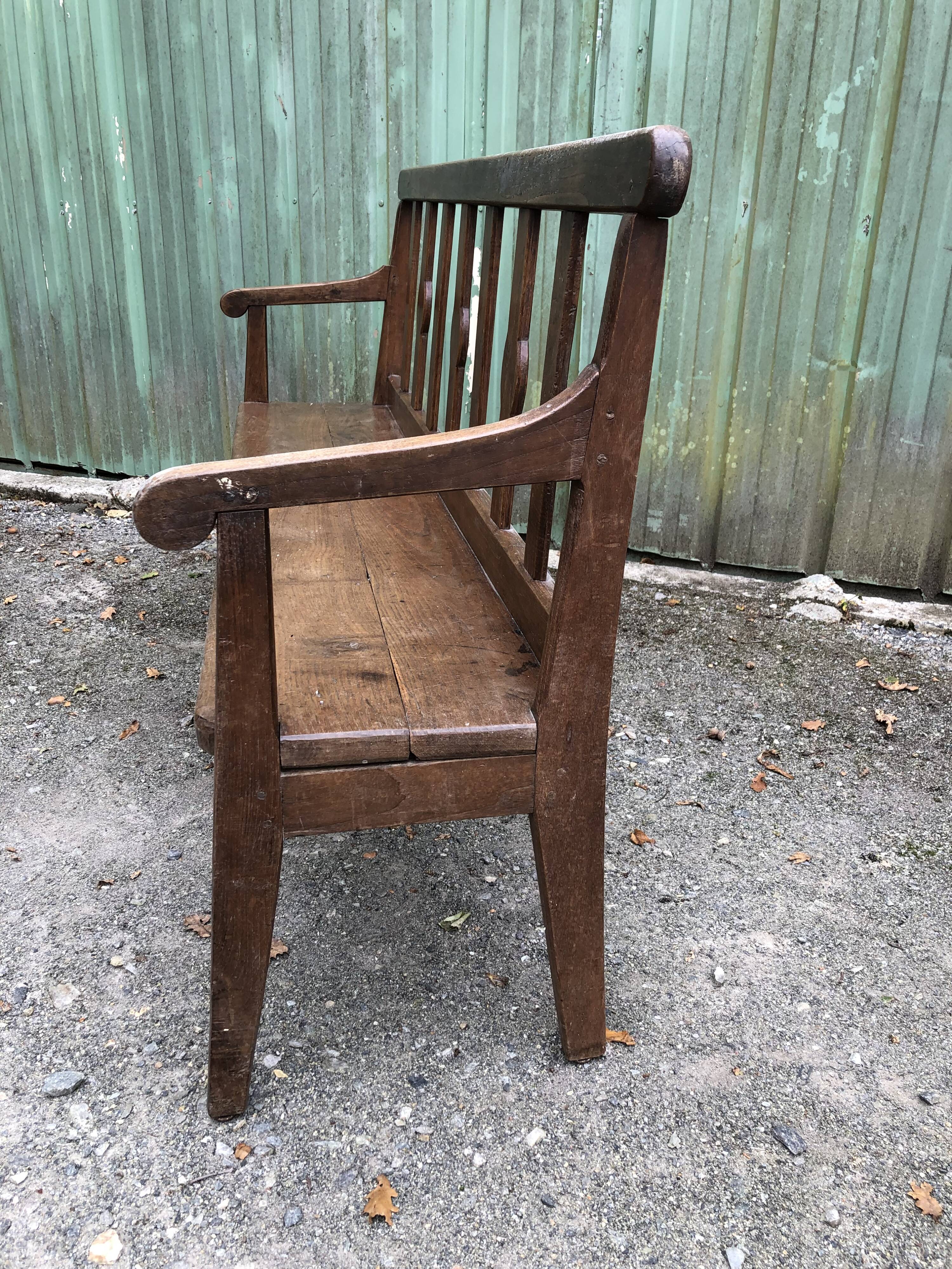 Duo of old solid oak benches with backs and armrests.