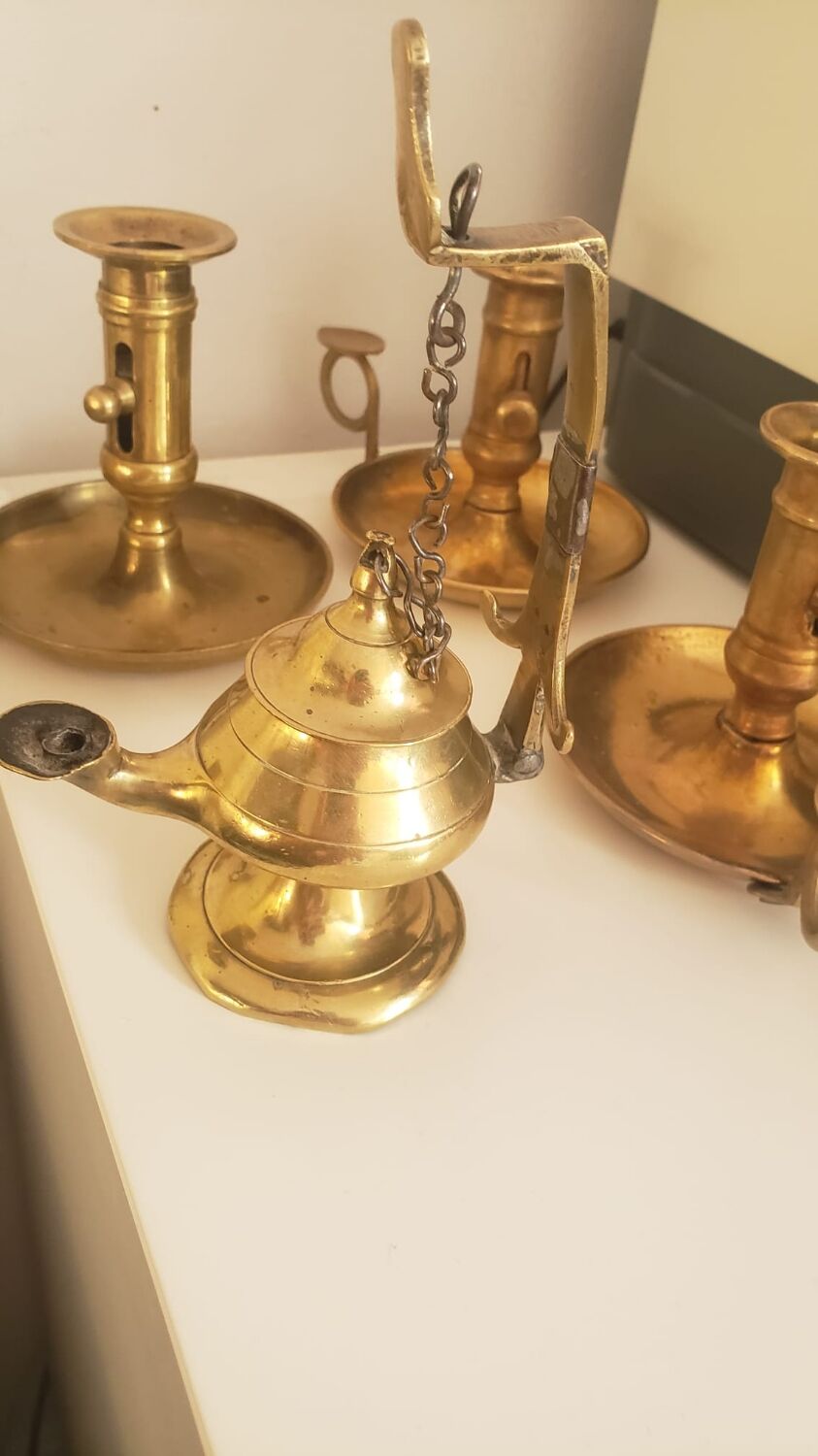 Many candlesticks and a small oil lamp.
