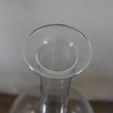 Antique glass carafe with a round belly and floral neck.