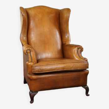 Old wingback armchair made of sheep leather in a correct condition