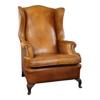 Old wingback armchair made of sheep leather in a correct condition