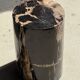 Black petrified wood side table with beige stripes and a semicircular shape.