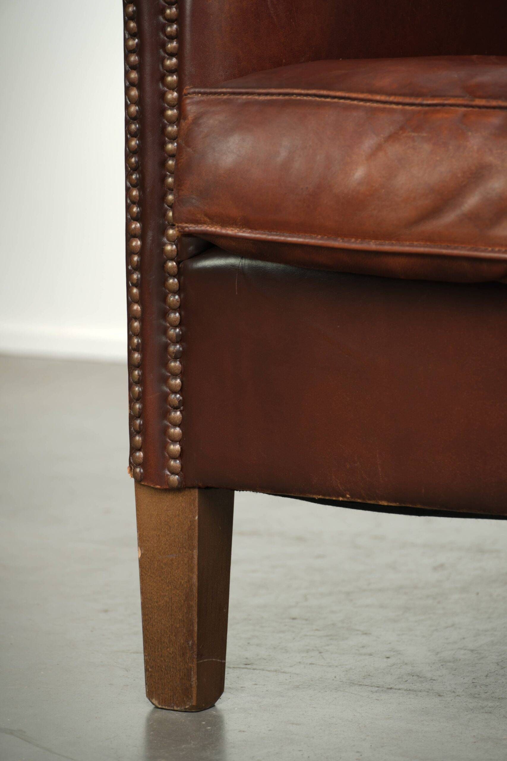 Characterful sheepskin club armchair in a dark cognac colour in English style
