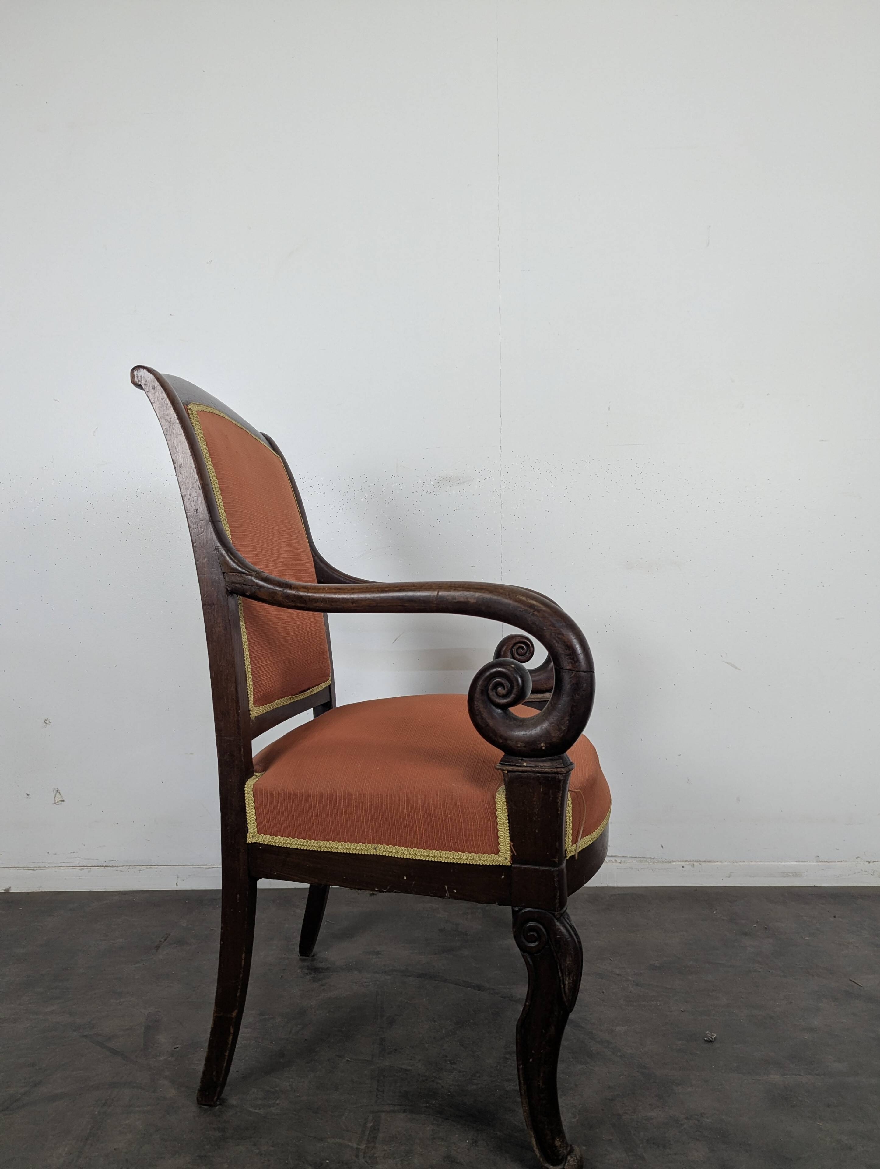 Restoration armchair in mahogany with cross arms and orange fabric.