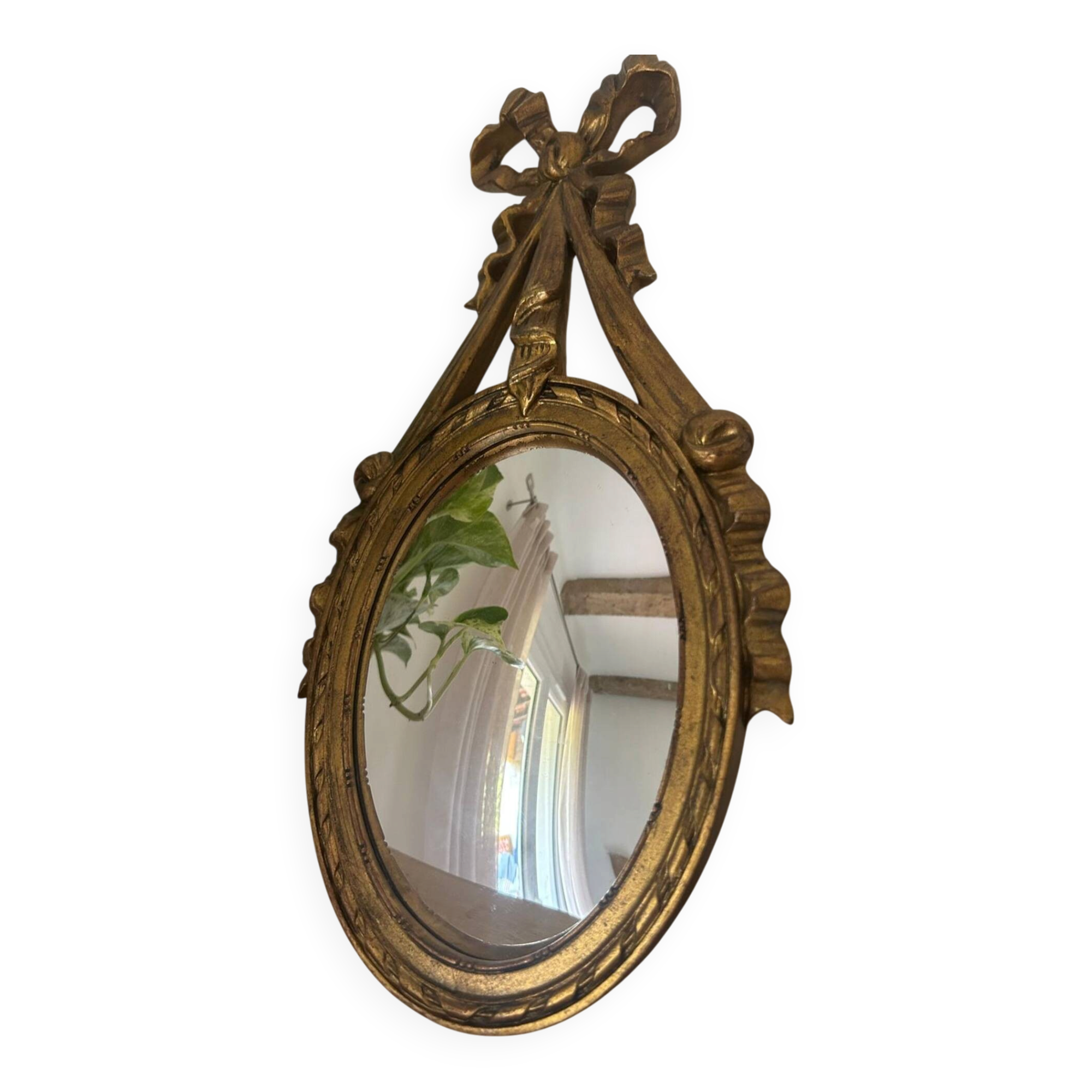 Oval convex witch mirror with golden ribbon mouldings.