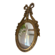 Oval convex witch mirror with golden ribbon mouldings.