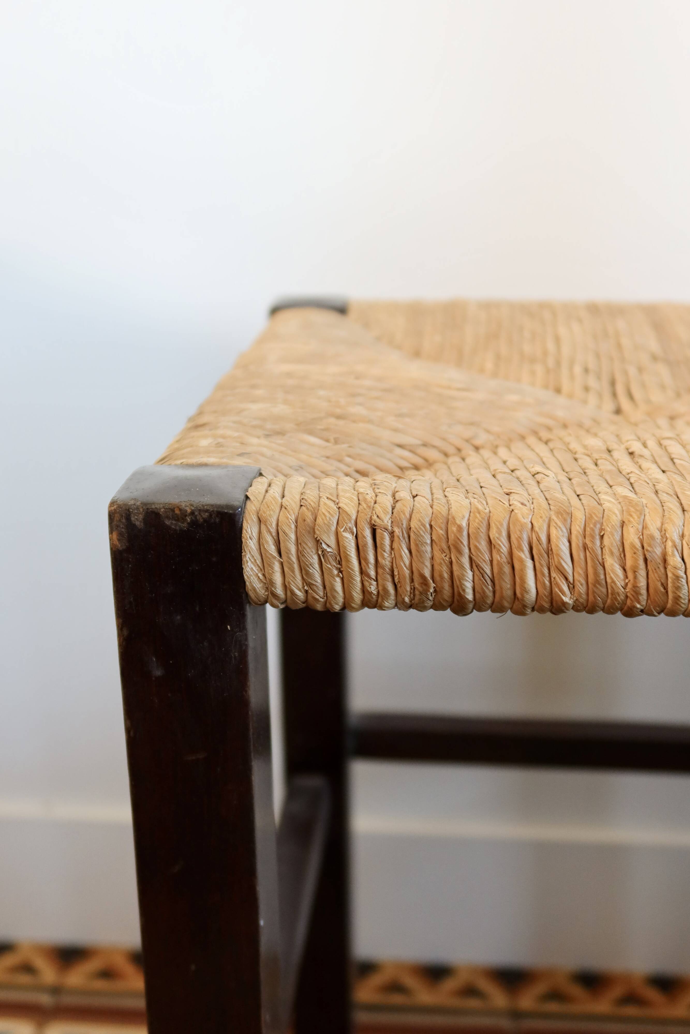 Vintage rustic stool in wood with a straw seat.