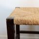 Vintage rustic stool in wood with a straw seat.
