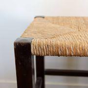 Vintage rustic stool in wood with a straw seat.
